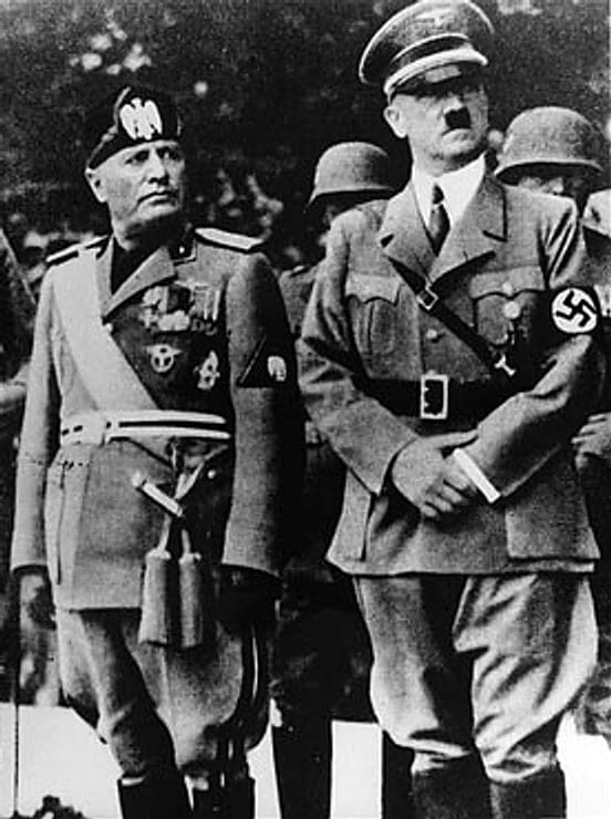 Benito Mussolini and Adolf Hitler stand together on an reviewing stand during Mussolini's official visit in Munich.